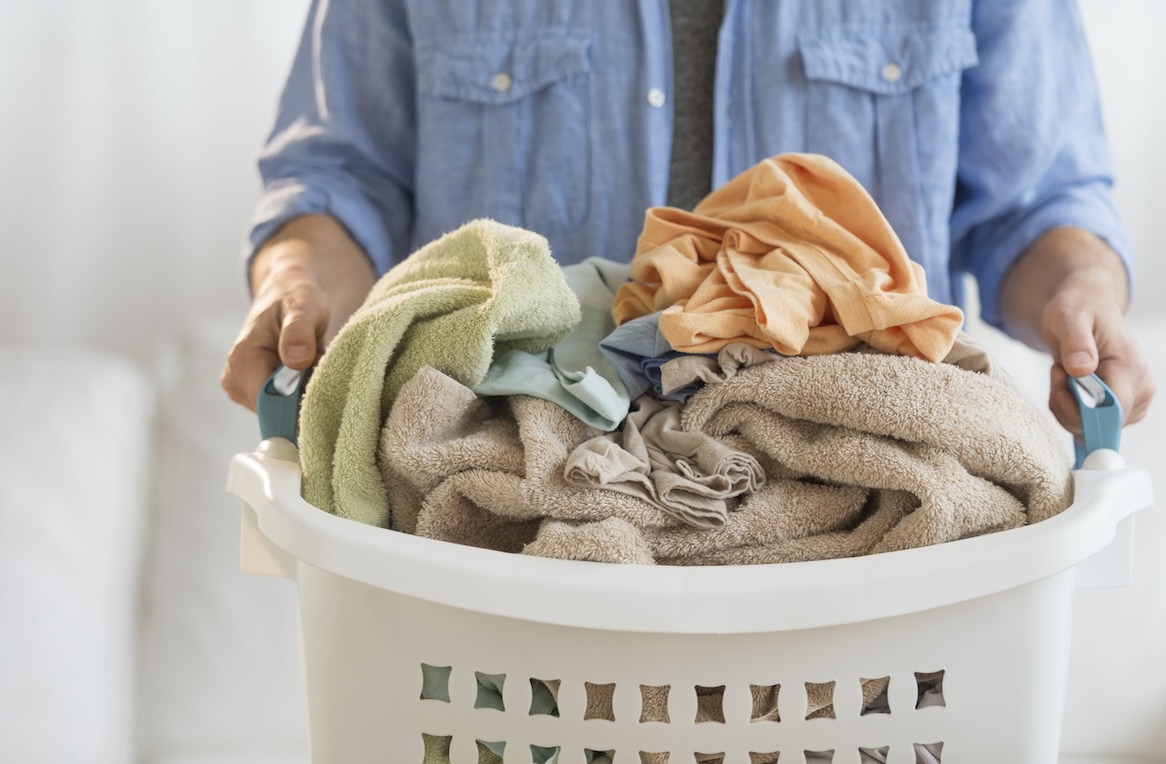 Person holding an overfilled laundry basket at home – ideal example of large household laundry loads that need commercial washers in Nashville.
